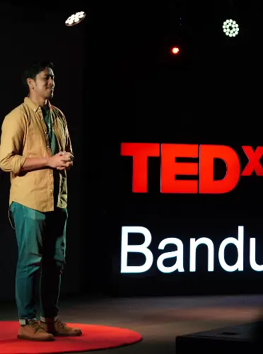 A speaker stands on the TEDxBandung stage