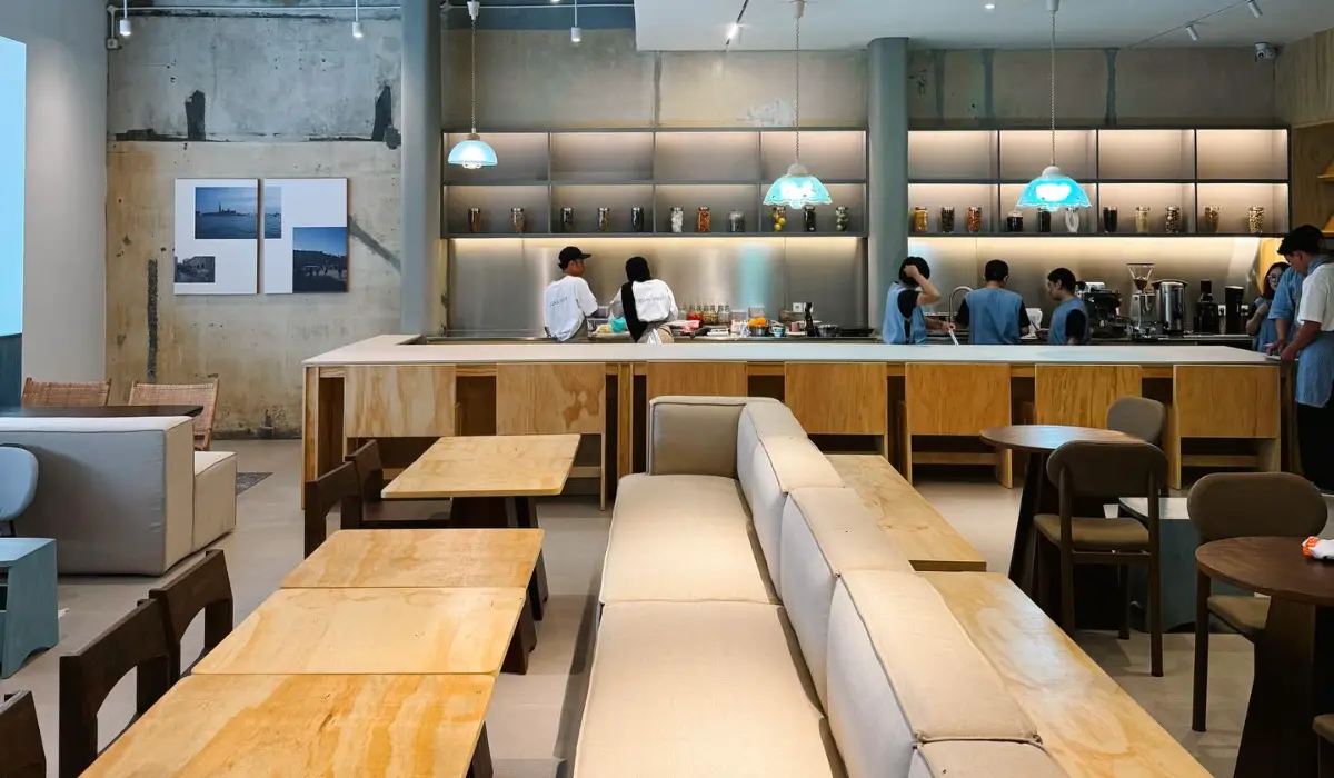 Modern café interior with warm wooden tables, cushioned seating, and an open bar area
