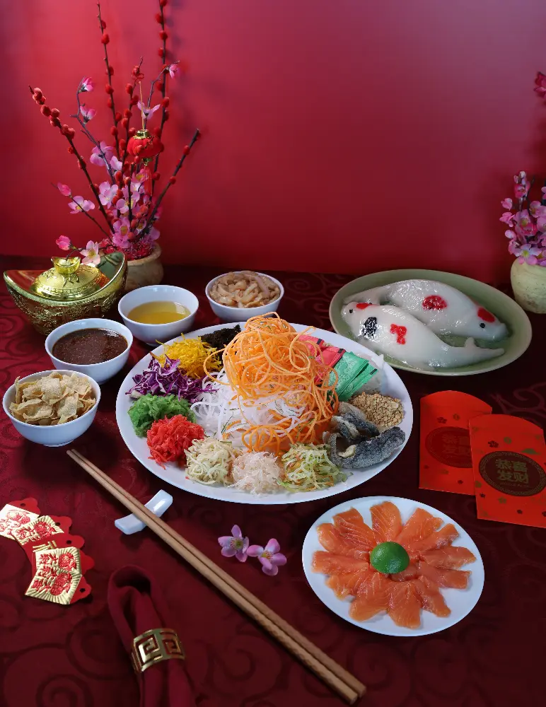 A festive Lunar New Year spread with yee sang, salmon sashimi, and traditional decorations.