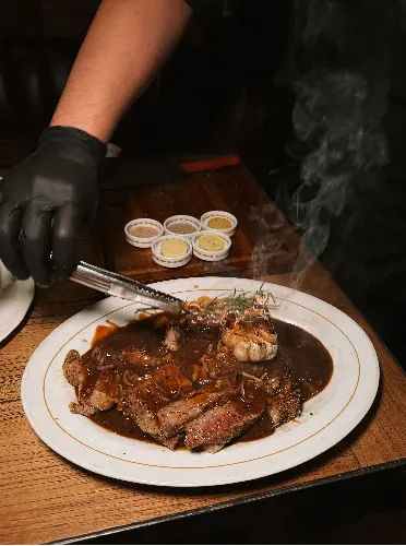 Chef plating Angus Prime Porterhouse steak - AOM Steakhouse