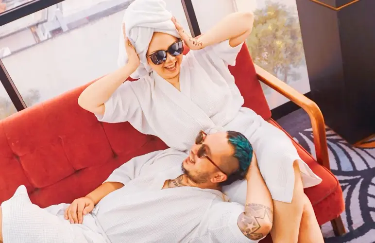 Couple in bathrobes relaxing on a red sofa