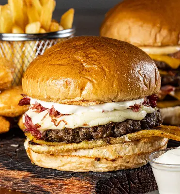 Juicy gourmet burgers with fries and nuggets on a wooden serving board.