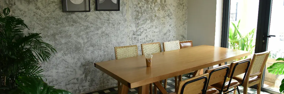 Minimalist private room with wooden table, mixed seating, and natural lighting at a cafe